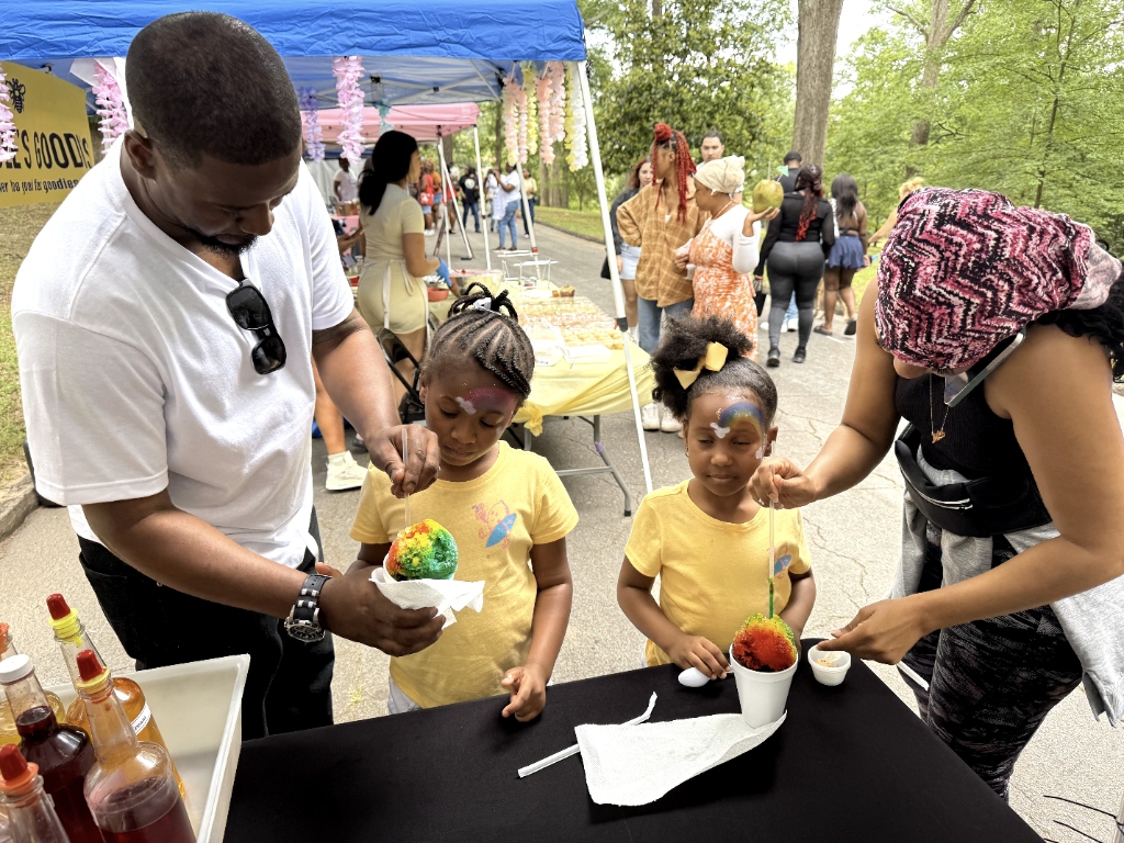 Twin girls enjoying colorful snoballs at outdoor event